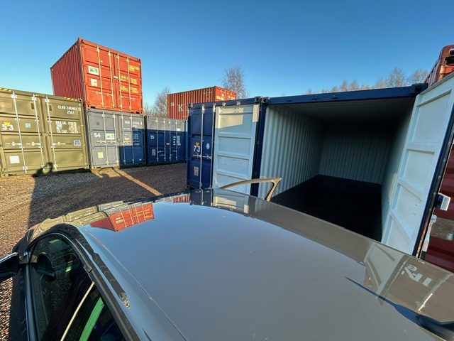 lots of shipping containers for self storage with a car loading into one of them