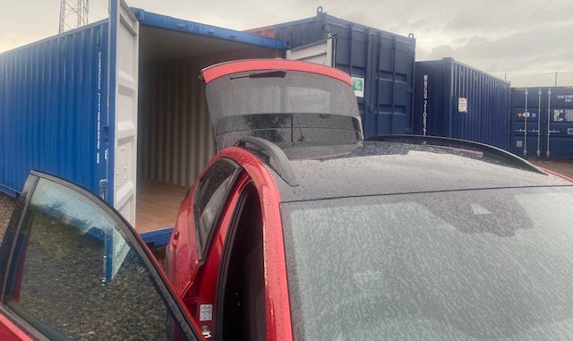 motor car with door and boot lid open about to unload goods into a storage unit