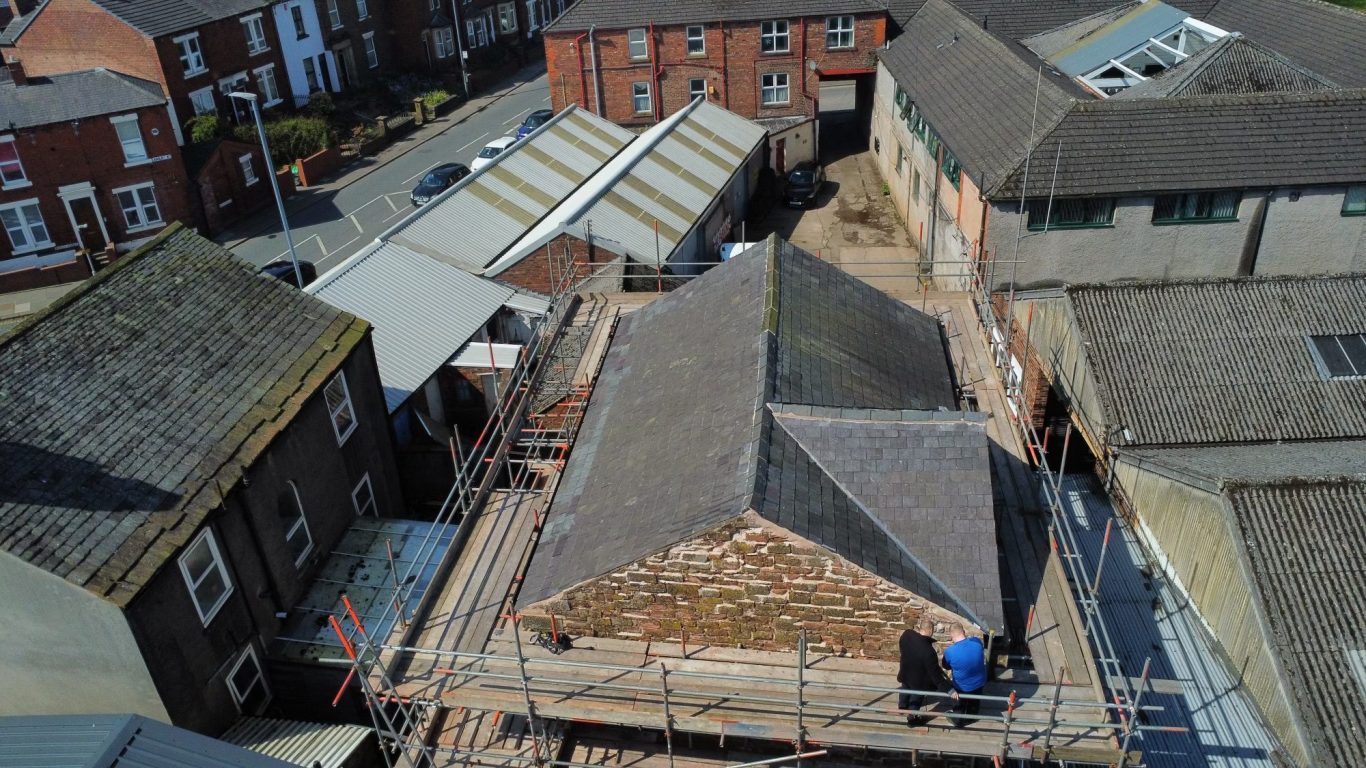 Roofing project underway on buildings in a town, with scaffolding surrounding the construction site.