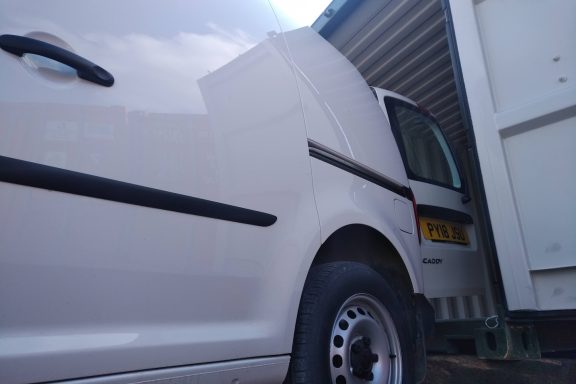 small van driven up to the doors of a shipping container