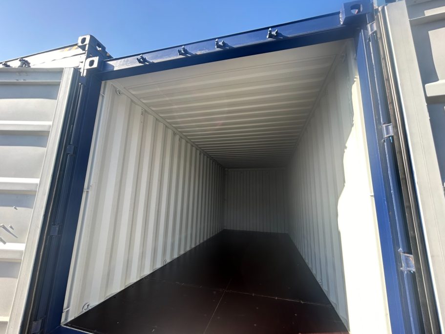 Empty shipping container viewed from the entrance, with clear blue sky above.