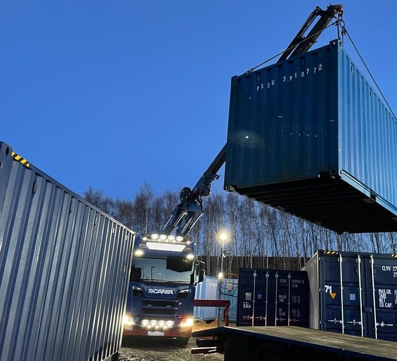 shipping container in mid air being positioned onto a storage facility