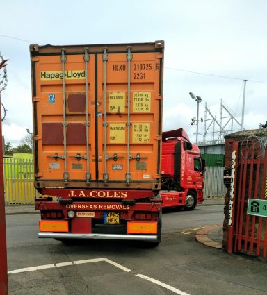 lorry driving out of storage site with a shipping container