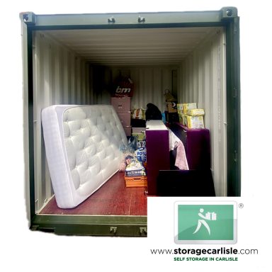 A storage container filled with a mattress, boxes, and other personal items.