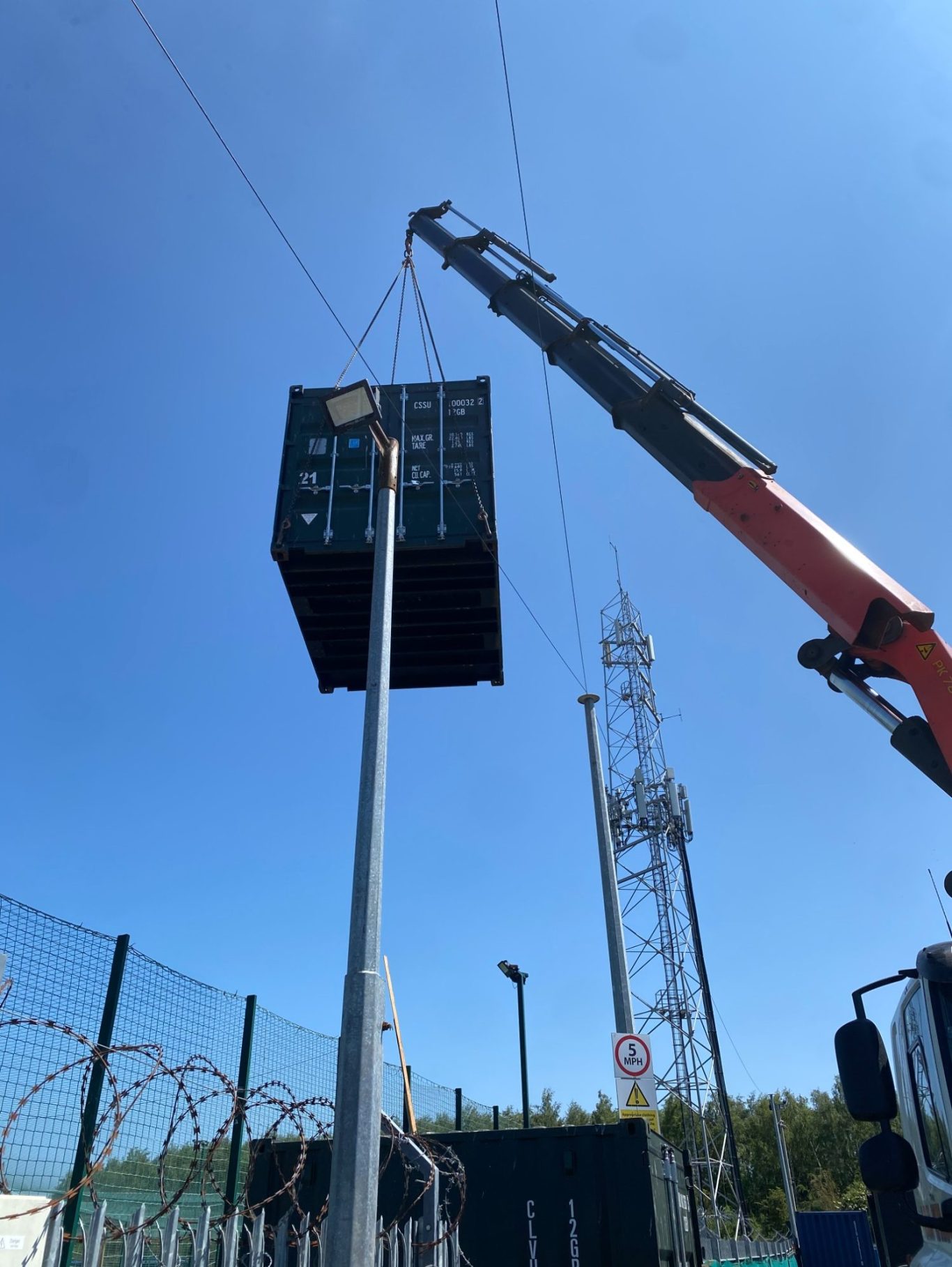 craine with a shipping container on chains