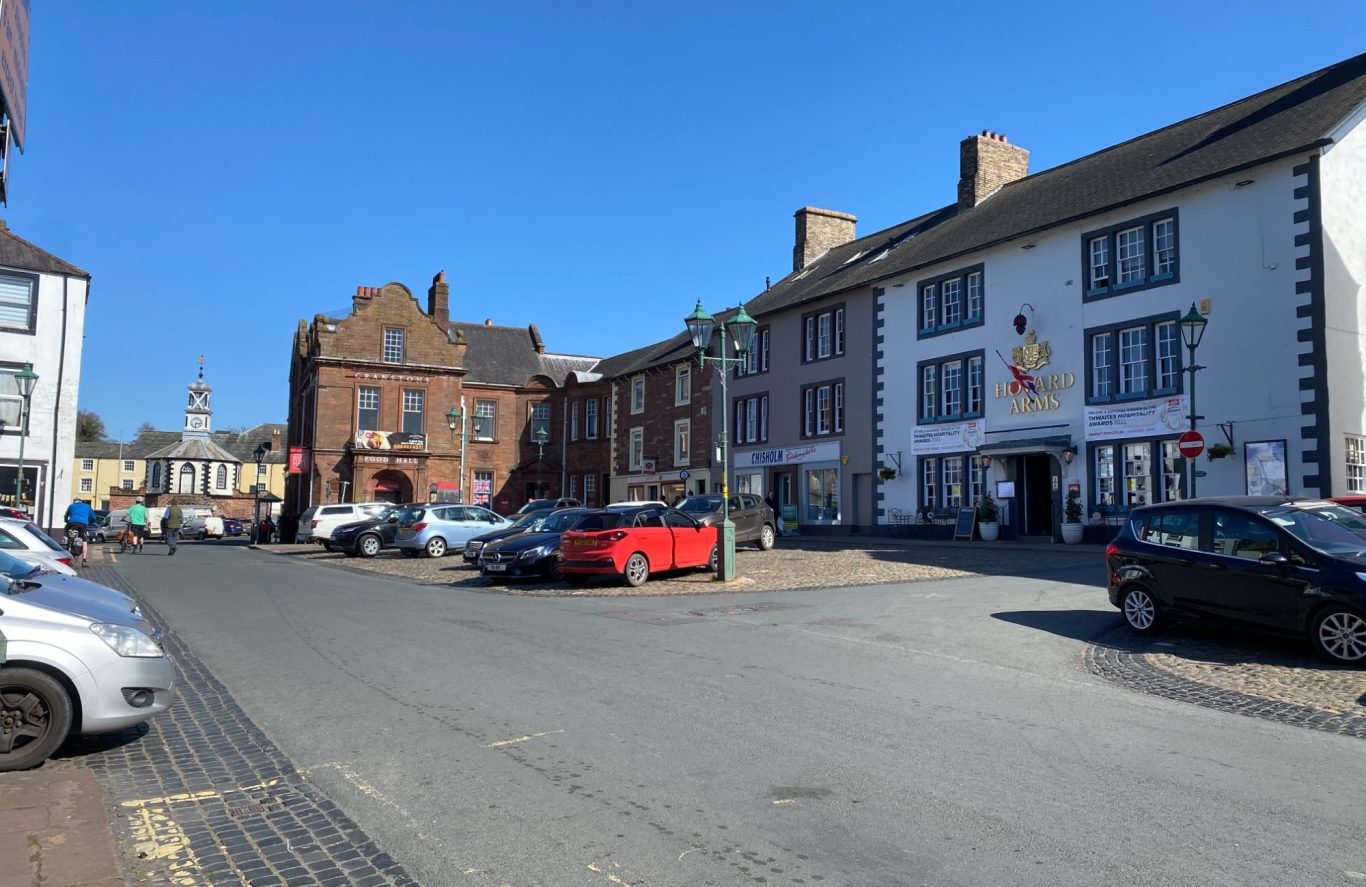 Brampton, Cumbria The village of Brampton, Cumbria with parked cars, historic buildings, and clear blue sky.