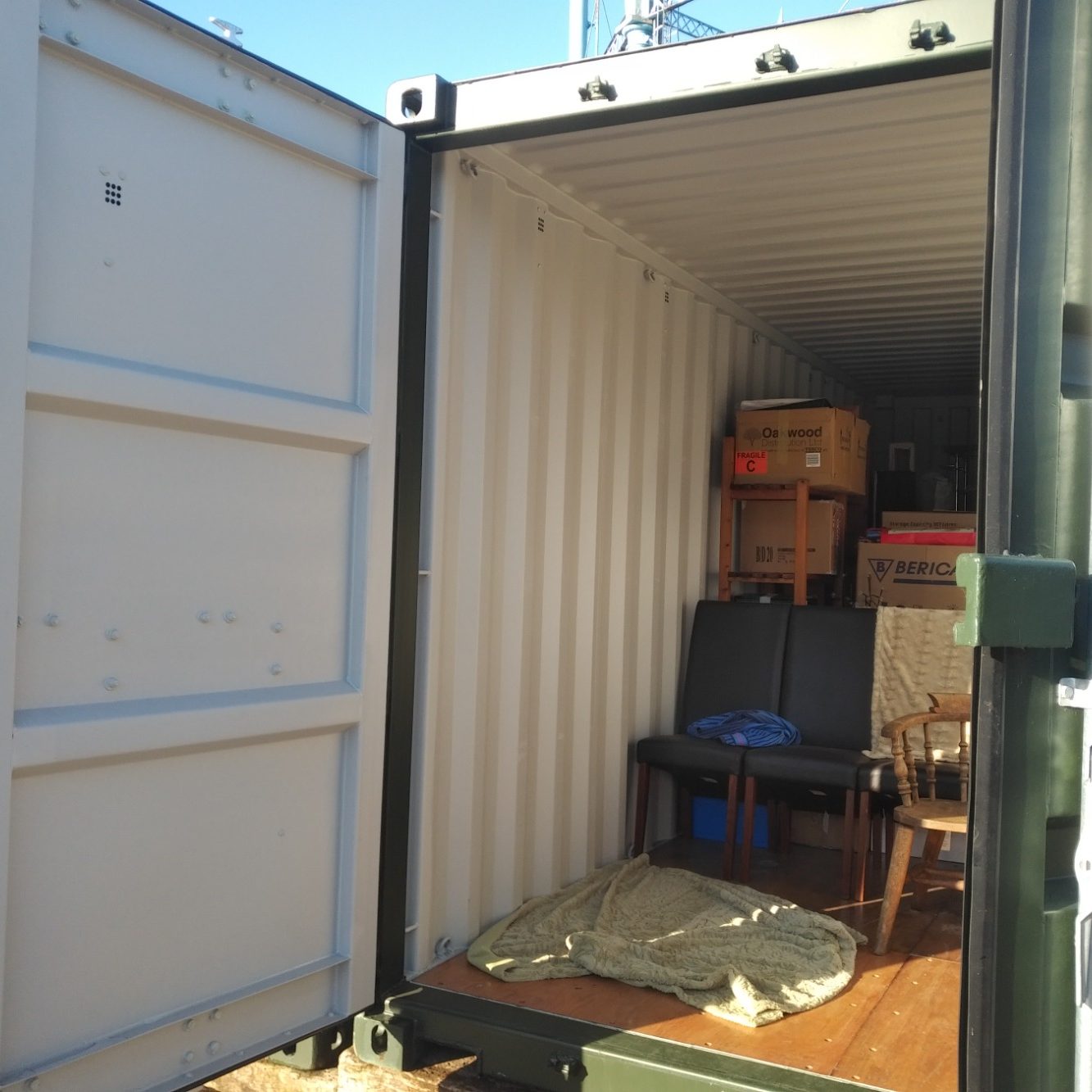 a shipping container with door open showing boxes and furniture
