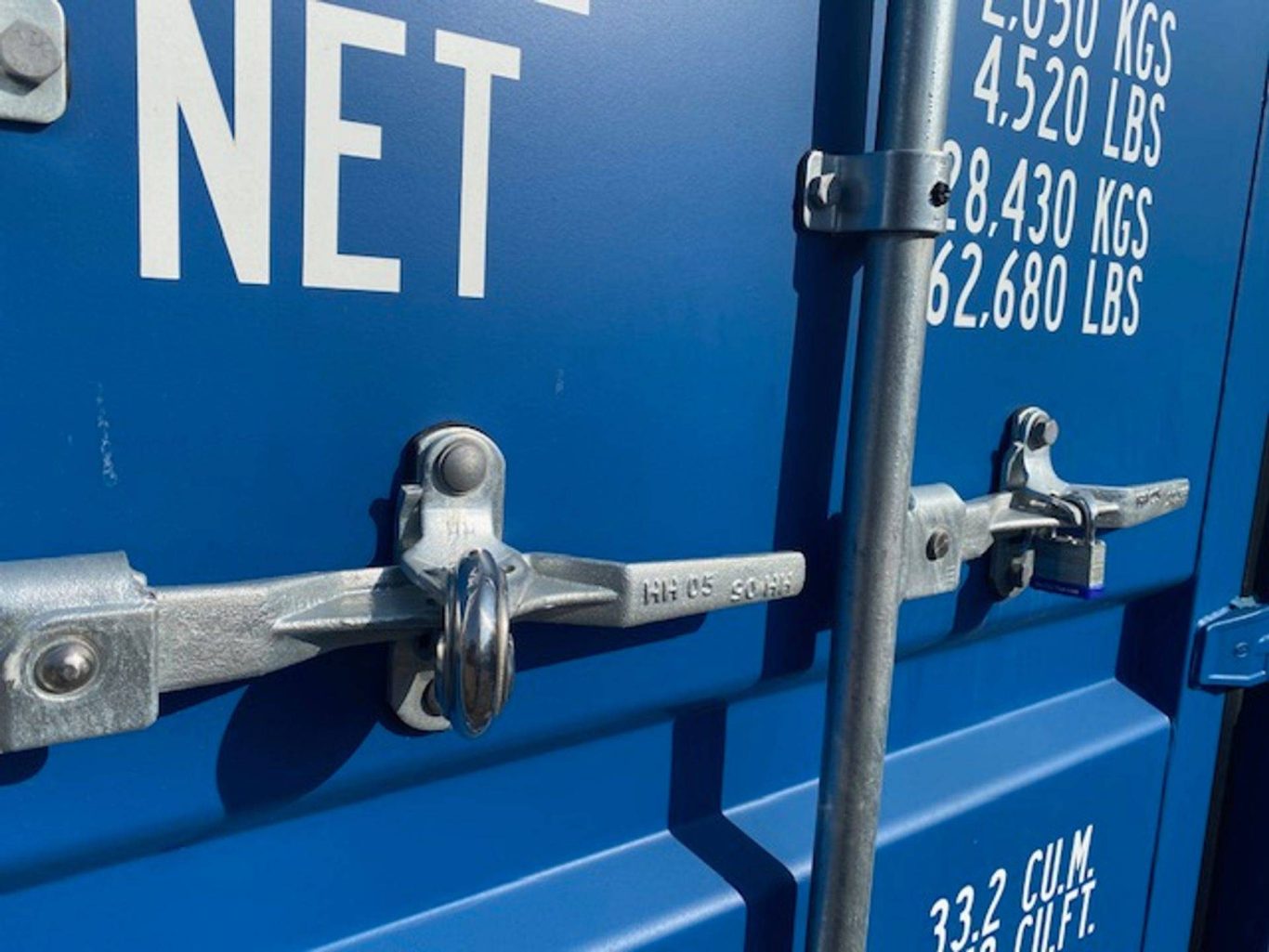Close-up of metal padlocks and handles on a blue shipping container.