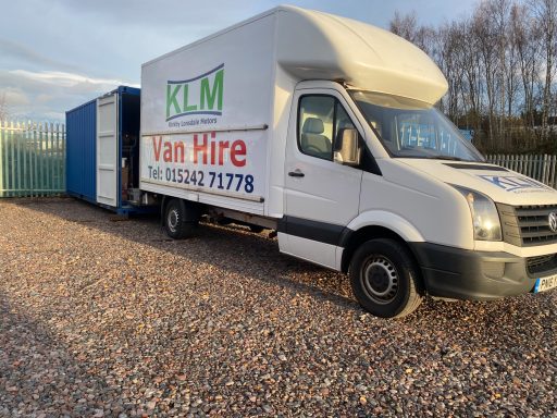 A white van with a blue trailer, displaying "Van Hire" signage.