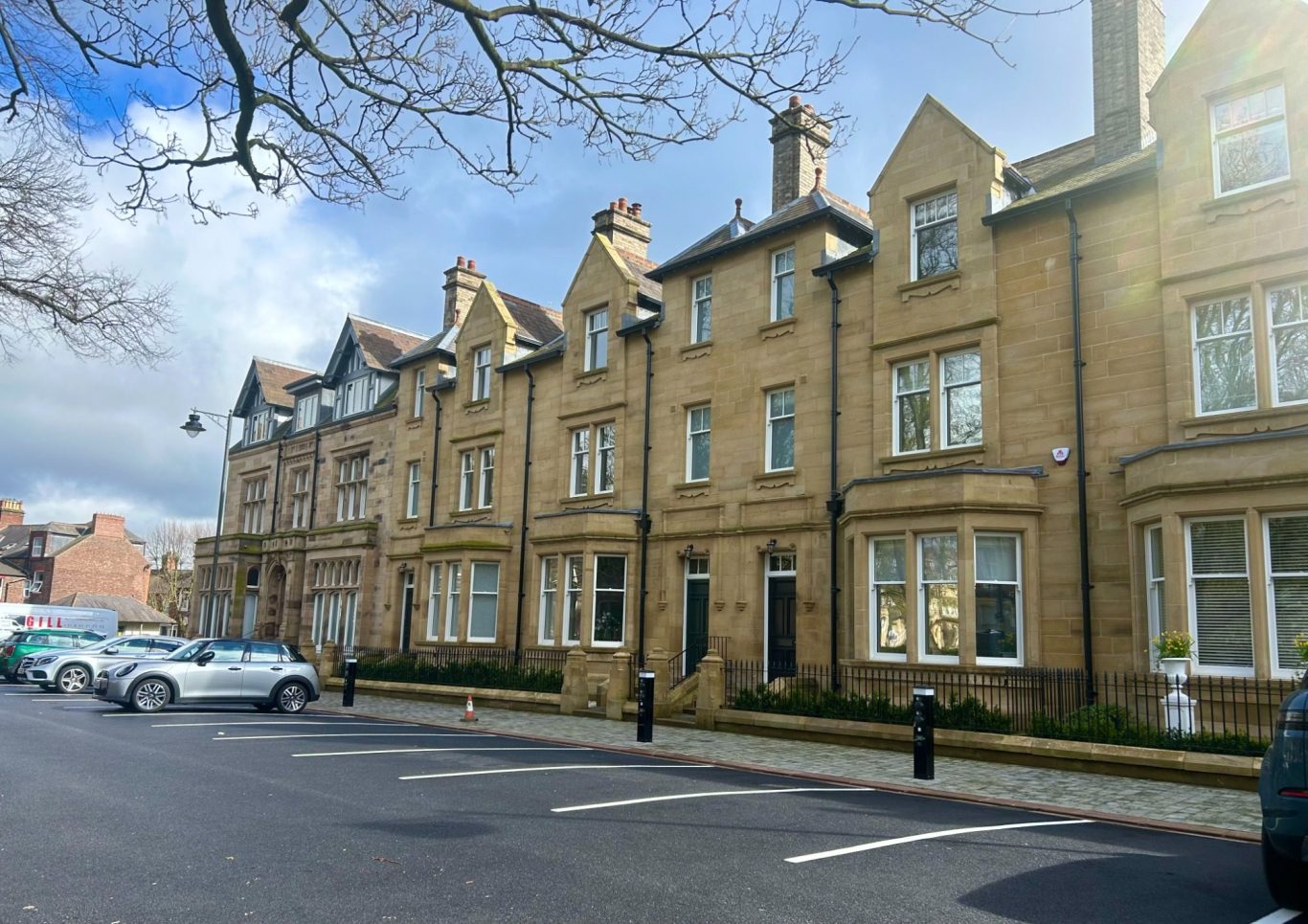 Row of historic brownstone buildings alongside a tree-lined street in Carlisle