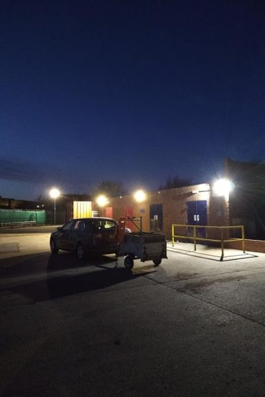 a yard with storage buildings at night illuminated