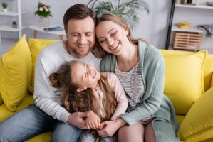 pleased family with daughter all sat on sofa 