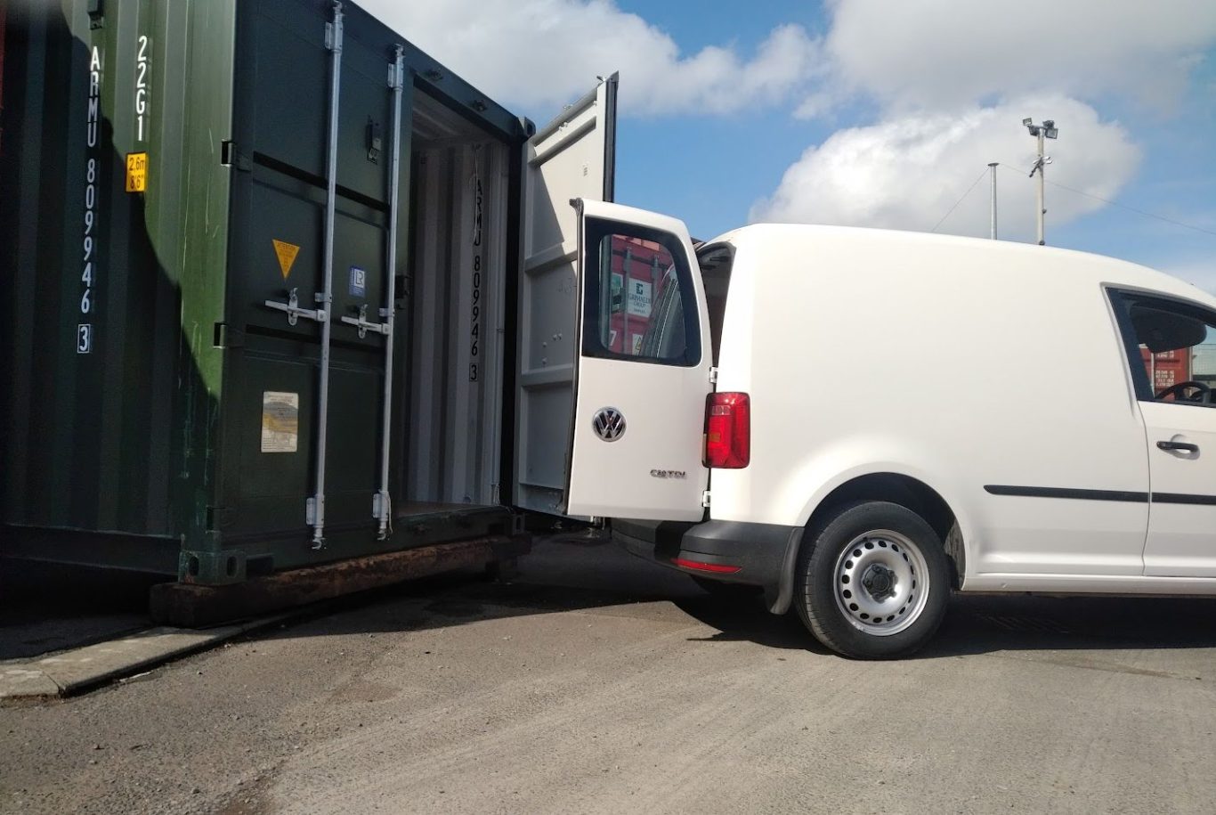small van reversing up to a shipping container