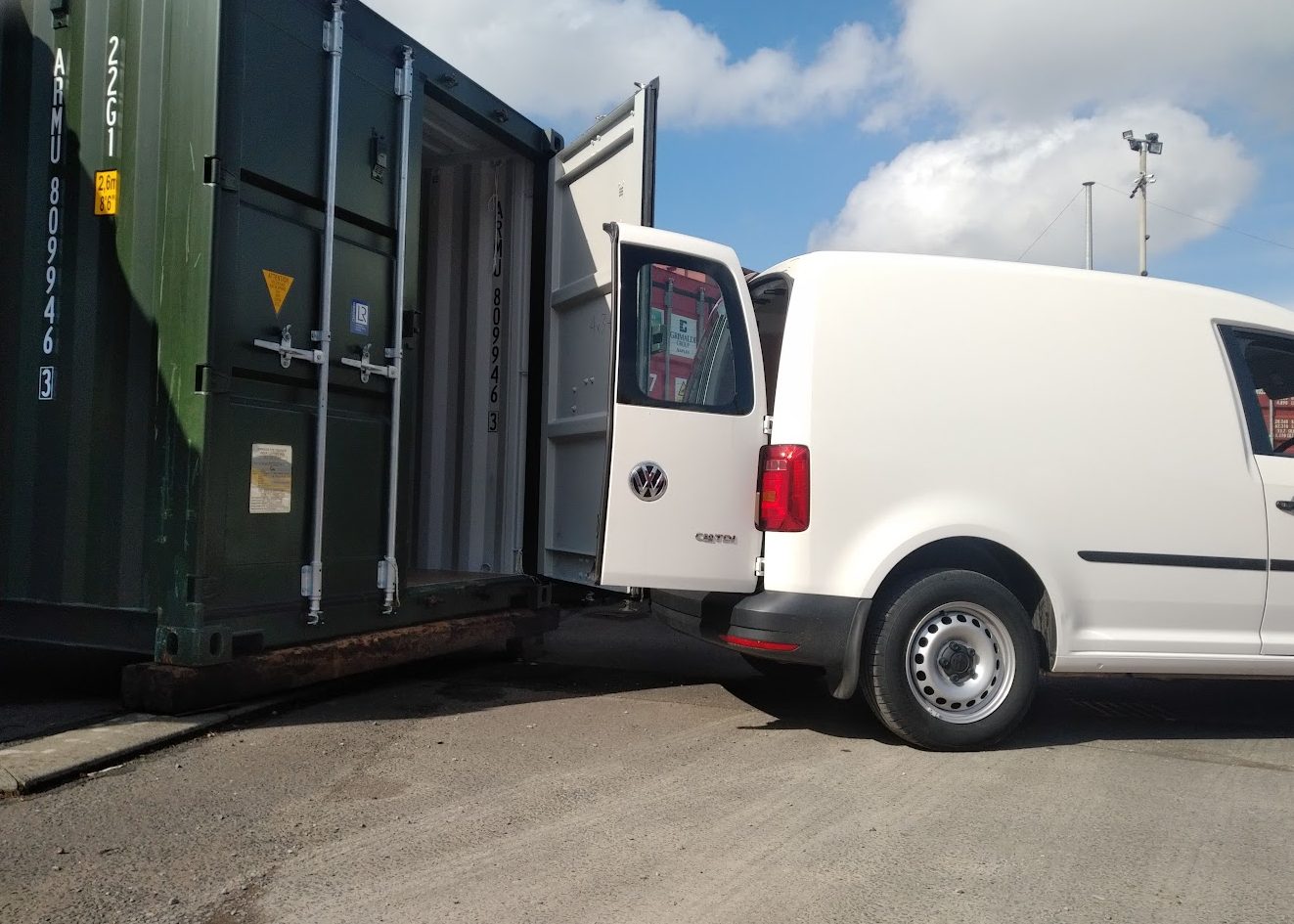 small van reversing up to a shipping container