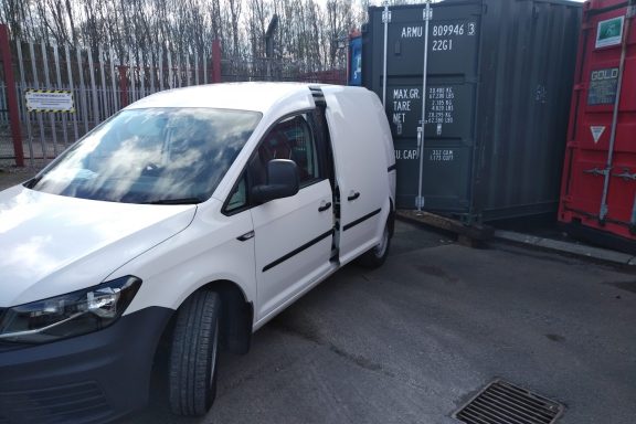 white small van beside a storage container