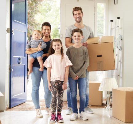 happy family in a house with dad carrying a box of contents