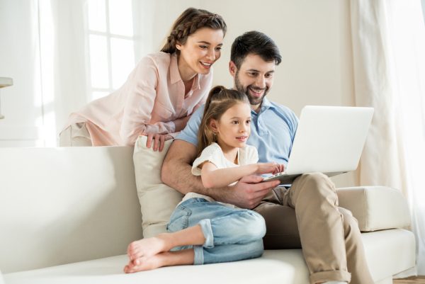 happy family sitting on a sofa using a laptop computer