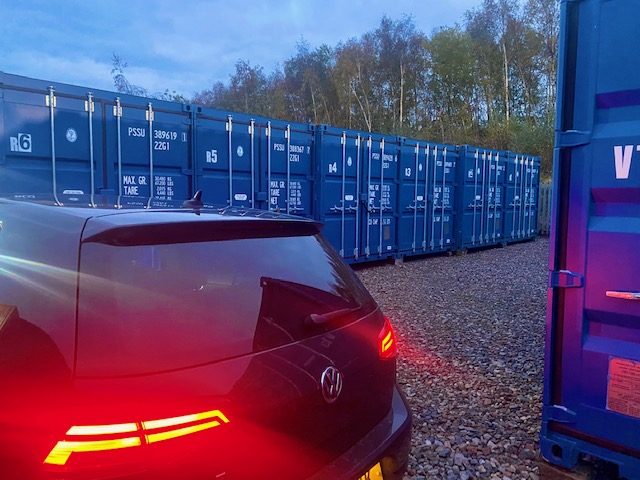 a car unloading furniture into a storage depot at dusk