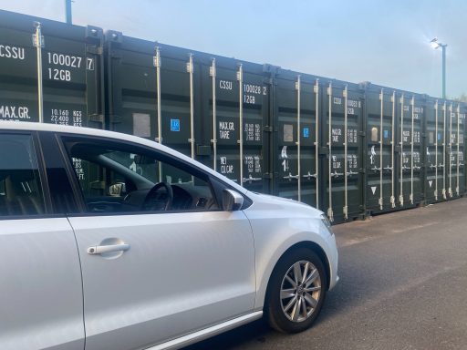 car stopped outside a row of green shipping containers used for self storage